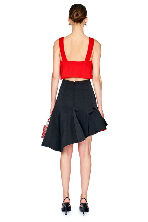 A woman shown from the back wearing a bright red sleeveless crop top and a black high-waisted flared skirt, paired with black heels and holding a small red handbag against a plain white background.