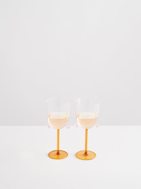 Two Maison Balzac pompom wine glasses half full of white wine