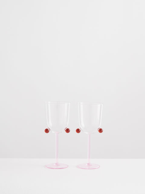 Two Maison Balzac wine glasses with pink stem and amber pompoms.