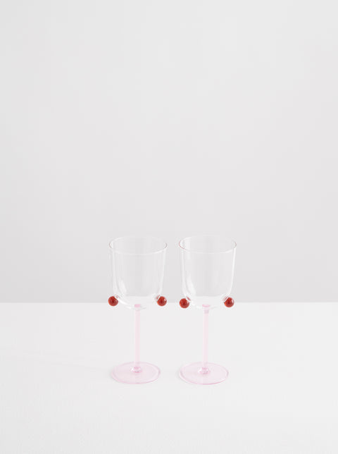 Two Maison Balzac pompom wine glasses in pink and amber.